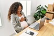 © Krakenimages.com - Young latin woman pregnant smiling confident touching tummy working at office