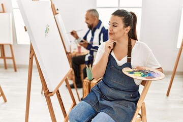 Sticker - Young artist woman at art studio serious face thinking about question with hand on chin, thoughtful about confusing idea