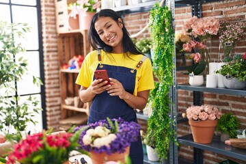 Poster - Young beautiful latin woman florist smiling confident using smartphone at florist