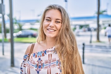 Wall Mural - Young blonde girl smiling happy standing at the city.