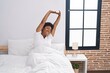 © Krakenimages.com - African american woman waking up stretching arms at bedroom