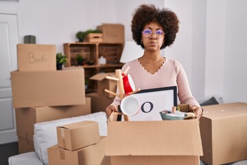 Wall Mural - Young african american woman moving to a new home puffing cheeks with funny face. mouth inflated with air, catching air.