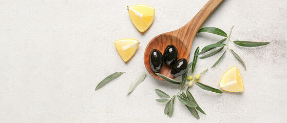 Wall Mural - Wooden spoon of tasty black olives and lemon pieces on light background
