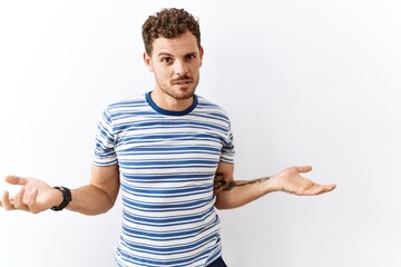 Sticker - Handsome young man standing over isolated background clueless and confused with open arms, no idea concept.