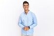 © Krakenimages.com - Young hispanic man wearing business shirt standing over isolated background with hands together and crossed fingers smiling relaxed and cheerful. success and optimistic