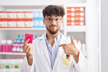 Sticker - Arab man with beard working at pharmacy drugstore holding condom depressed and worry for distress, crying angry and afraid. sad expression.