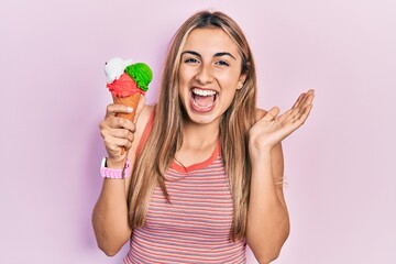 Sticker - Beautiful hispanic woman holding ice cream celebrating achievement with happy smile and winner expression with raised hand