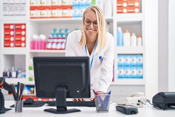 Poster - Young blonde woman pharmacist using computer working at pharmacy