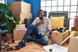 © Krakenimages.com - African american man sitting on the floor at new home cheerful with a smile on face pointing with hand and finger up to the side with happy and natural expression