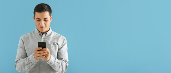 Wall Mural - young man with mobile phone on blue background with space for text