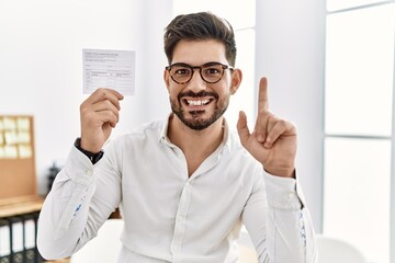 Poster - Young man with beard holding covid record card surprised with an idea or question pointing finger with happy face, number one