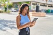 © Krakenimages.com - Young beautiful hispanic woman using touchpad at street