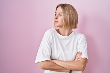 Sticker - Young caucasian woman standing over pink background looking to the side with arms crossed convinced and confident