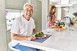 © Krakenimages.com - Middle age hispanic couple eating healthy meal at home looking positive and happy standing and smiling with a confident smile showing teeth