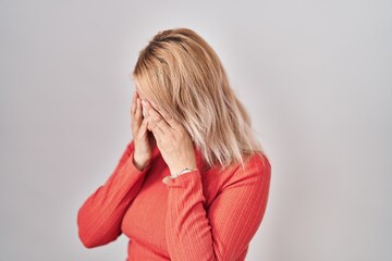 Canvas Print - Blonde woman standing over isolated background with sad expression covering face with hands while crying. depression concept.