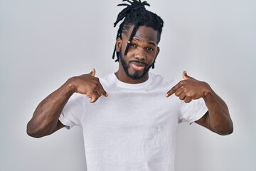 Wall Mural - African man with dreadlocks wearing casual t shirt over white background looking confident with smile on face, pointing oneself with fingers proud and happy.