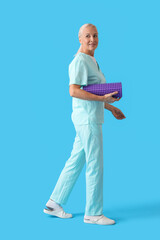 Poster - Mature physiotherapist with foam roller on blue background