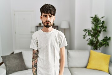 Poster - Hispanic man with beard at the living room at home depressed and worry for distress, crying angry and afraid. sad expression.