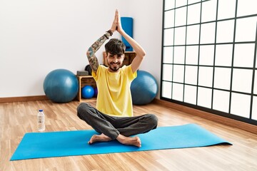 Sticker - Young hispanic man smiling confident training yoga at center.