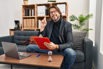 Poster - Handsome middle age man working at consultation office smiling amazed and surprised and pointing up with fingers and raised arms.