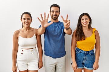 Sticker - Group of young hispanic people standing over isolated background showing and pointing up with fingers number seven while smiling confident and happy.