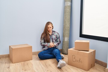 Sticker - Young blonde woman sitting on the floor moving to a new home with hand on stomach because indigestion, painful illness feeling unwell. ache concept.