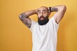 © Krakenimages.com - Young hispanic man with beard and tattoos standing over yellow background crazy and scared with hands on head, afraid and surprised of shock with open mouth