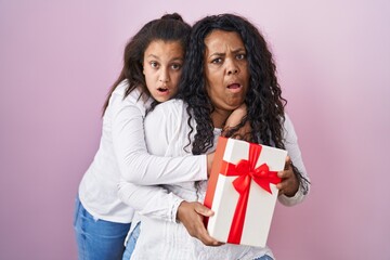 Sticker - Mother and young daughter holding with presents in shock face, looking skeptical and sarcastic, surprised with open mouth