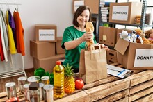Brunette Woman With Down Syndrome Putting Donated Food In Paper Bag At Donations Stand