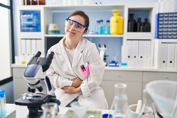 Sticker - Hispanic girl with down syndrome working at scientist laboratory with hand on stomach because indigestion, painful illness feeling unwell. ache concept.