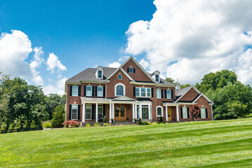 Large country house and summer landscape with a perfect lawn. Blue sky and white clouds.