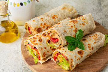 Poster - Closeup of Wraps with a soft flatbread rolled around a filling with vegetables and cheese, tomato, fried eggplant, lettuce. Vegetarian food concept.