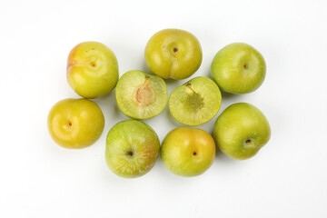 Canvas Print - Small mini green fresh juicy plum fruit on white background cut slice half seed many pile