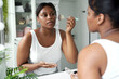 © gpointstudio - African-American woman applying make up blusher in the bathroom