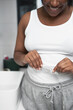© gpointstudio - Close up of unrecognizable African-American woman standing in the bathroom and taking measures on her waist