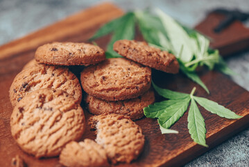 Cannabis food cookies with cannabis leaf marijuana herb on wooden background, delicious sweet dessert cookie with hemp leaf plant THC CBD herbs food snack and medical concept