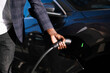 © Westend61 - Hand of man plugging charger into electric car