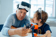© Westend61 - Senior man with VR glasses examining robot model by grandson at home