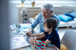 © Westend61 - Boy drawing on tablet PC by grandfather in living room