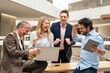 © Westend61 - Cheerful business colleagues celebrating success in corridor