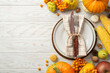 Thanksgiving day concept. Top view photo of plate knife fork napkin raw vegetables pumpkins zucchini corn pattypans apple pear walnut acorn pine cones rowan on isolated white wooden table background