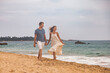 © Alex Vog - Happy couple together holding hands on tropical sandy beach at sea sunset background. Beauty couple enjoying honeymoon summer at ocean coastline. Lovely man and woman relaxing happiness. Copy space