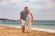 © Alex Vog - Happy couple together having on tropical sandy beach at sea sunset background. Beauty couple enjoying honeymoon summer at ocean coastline. Lovely man and woman relaxing happiness. Copy text space