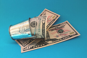 Wall Mural - Miniature bucket with dollars on a blue background.