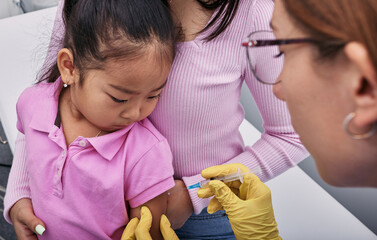 routine vaccinations for child. asian girl and her mother while vaccinated by general practitioner i