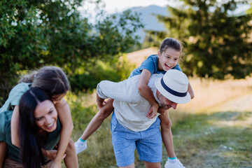 Wall Mural - Happy parents giving their children piggyback ride in summer in nature.