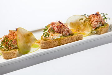 Wall Mural - Aesthetic composition with crab bruschetta on white background over white wall. Italian bruschetta with crab, avocado and cheese on fine dining in summer. Elegant menu concept.