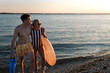 © Halfpoint - Happy young couple in swimsuits posing with swimming wheel, at beach during sunset.