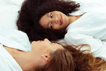 Caucasian and black women love together and lying on bed as diversity person. Young Adult Romantic couple look at each other face and express feeing happy smile and diversity freedom, copy space