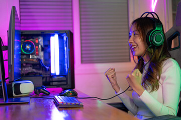 Asian gamer playing online video game winning excited on PC with lighting effect, broadcast streaming live at home. Gamer and E-Sport online gaming technology Championship tournament gamer concept.